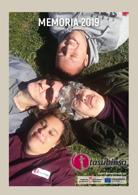 Cuatro personas de Tasubinsa, sonrientes y tumbadas en la hierba